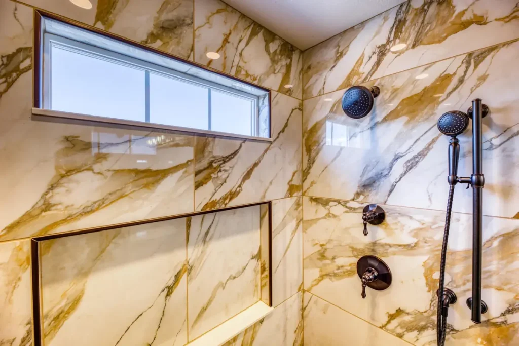 Shower with large gold-veined marble-look tile, a niche, and black fixtures